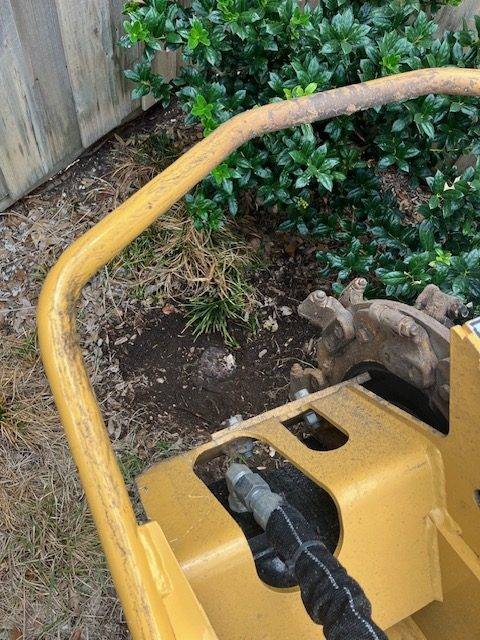 Compact stump grinder working along a fence line